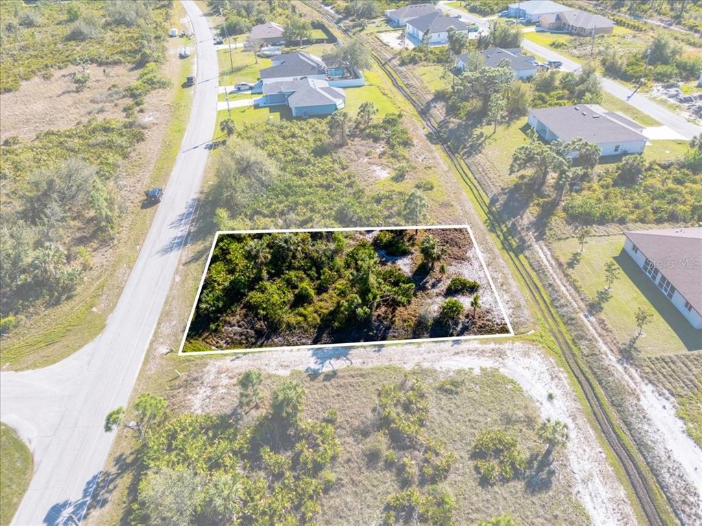 An aerial view shows a rectangular, undeveloped lot covered in vegetation next to a paved road — 9243 WALDREP STREET, PORT CHARLOTTE, FL