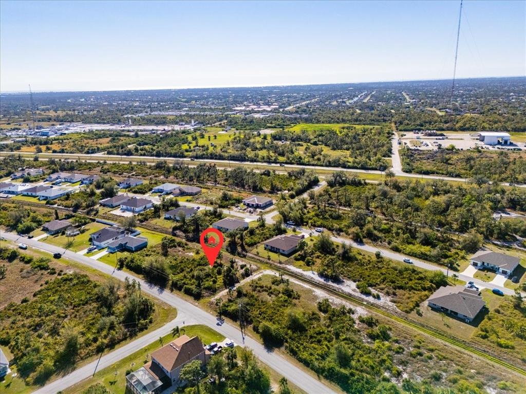 An aerial view shows a vacant, wooded residential lot marked with a red pin — 9243 WALDREP STREET, PORT CHARLOTTE, FL