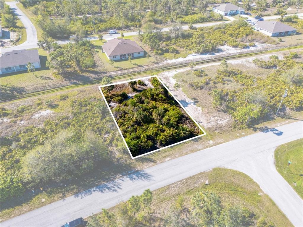 An aerial view shows a rectangular, undeveloped lot surrounded by vegetation and nearby houses — 9243 WALDREP STREET, PORT CHARLOTTE, FL
