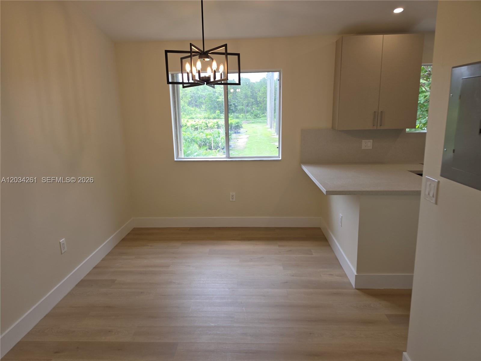 A dining area features light wood flooring, a modern chandelier, and an adjacent kitchen counter — 13318 SW 152nd St # 3202, Miami FL 33177, MIAMI, FL