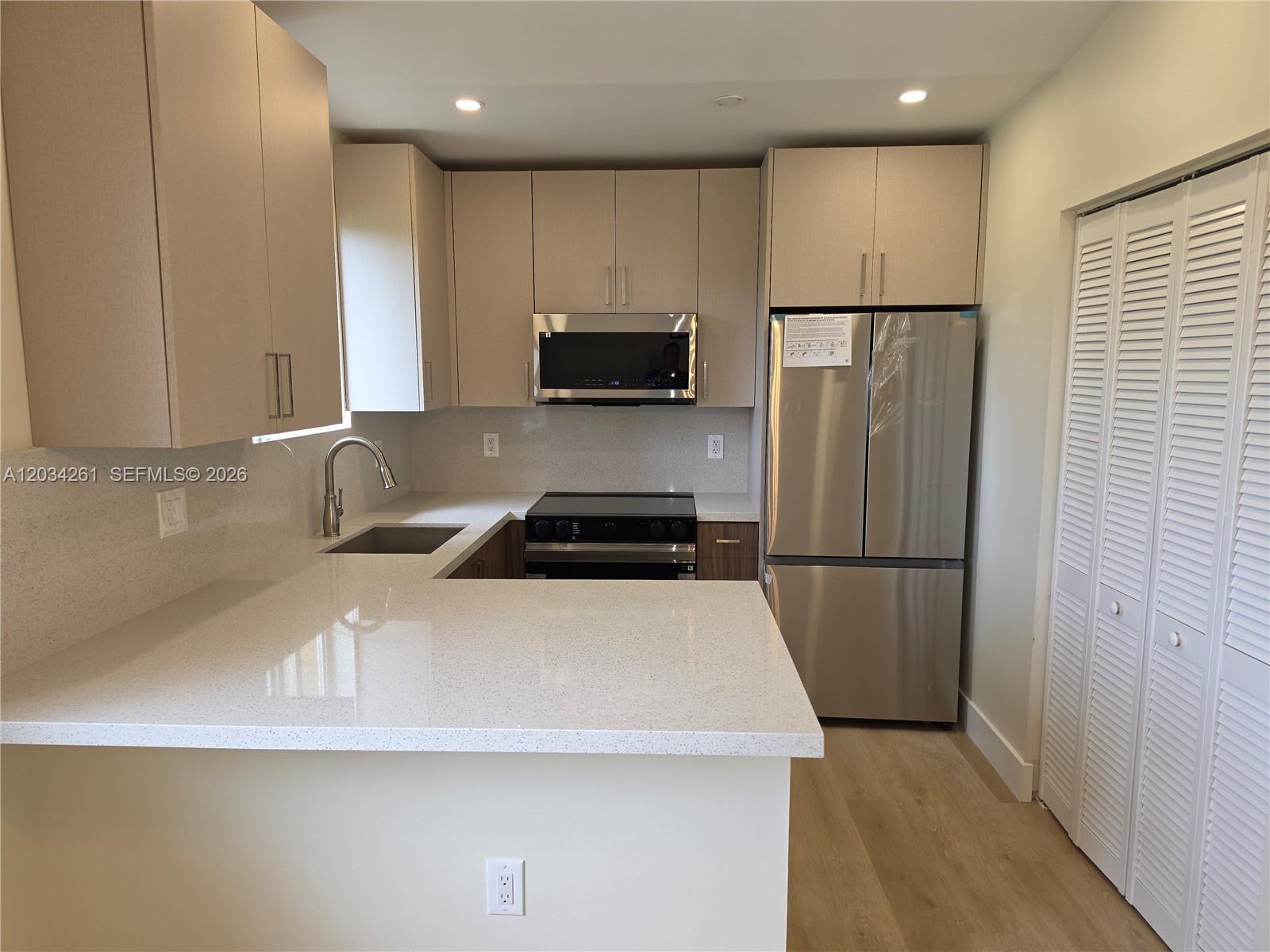 A modern kitchen features light-toned cabinetry, stainless steel appliances, and white quartz countertops — 13318 SW 152nd St # 3202, Miami FL 33177, MIAMI, FL