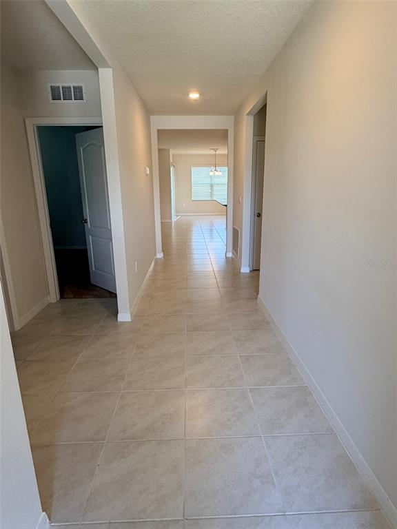 A tiled hallway leads from the entryway toward a bright living area with a window — 430 TANIS AVENUE, ST CLOUD, FL