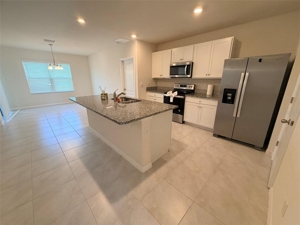 A kitchen features white cabinets, granite countertops, a center island, and stainless steel appliances — 430 TANIS AVENUE, ST CLOUD, FL