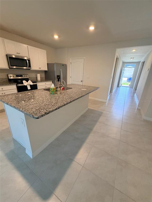 A kitchen with granite countertops, white cabinets, stainless steel appliances, and tile flooring — 430 TANIS AVENUE, ST CLOUD, FL