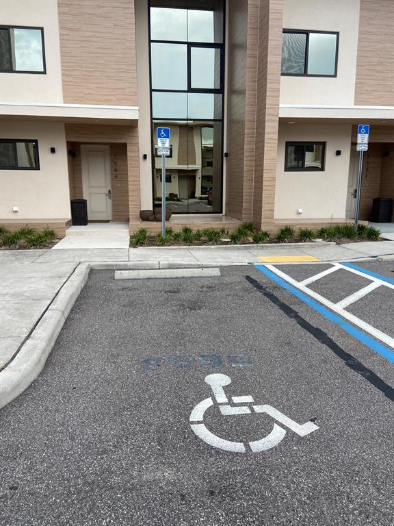 An exterior view of a modern building with two accessible parking spaces in the foreground — 7582 BROOKLYN DRIVE, KISSIMMEE, FL