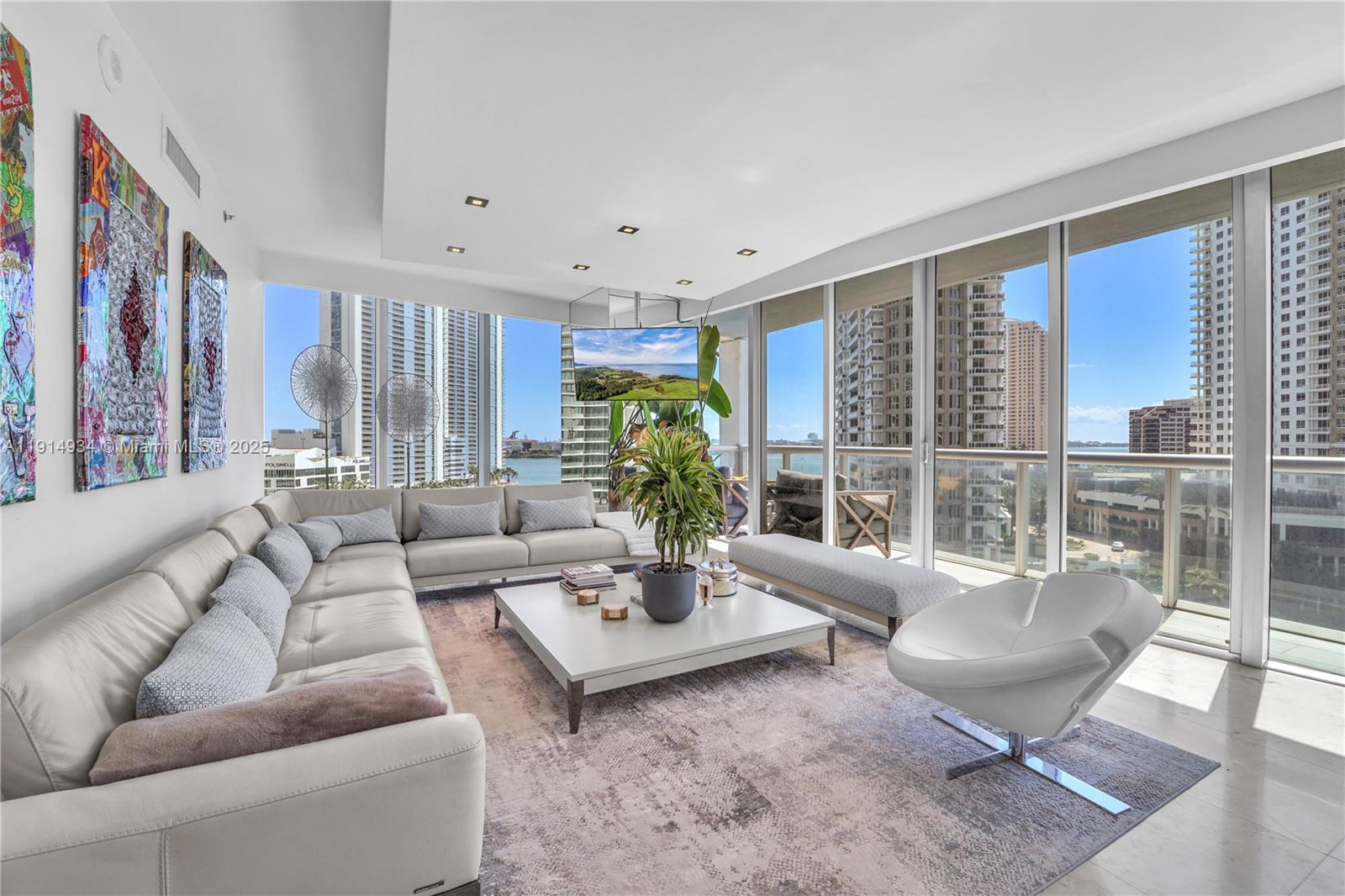 A modern living room features a large sectional sofa, white coffee table, and floor-to-ceiling windows — 465 Brickell Ave # 1001, Miami FL 33131, MIAMI, FL