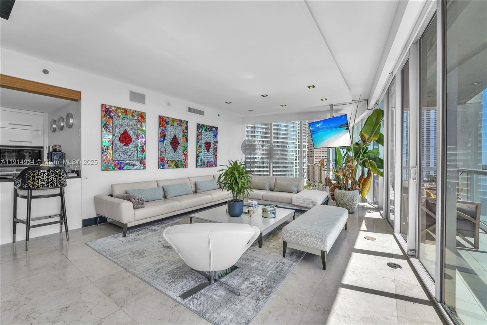 A modern living room features a large sectional sofa, artwork, and floor-to-ceiling windows — 465 Brickell Ave # 1001, Miami FL 33131, MIAMI, FL