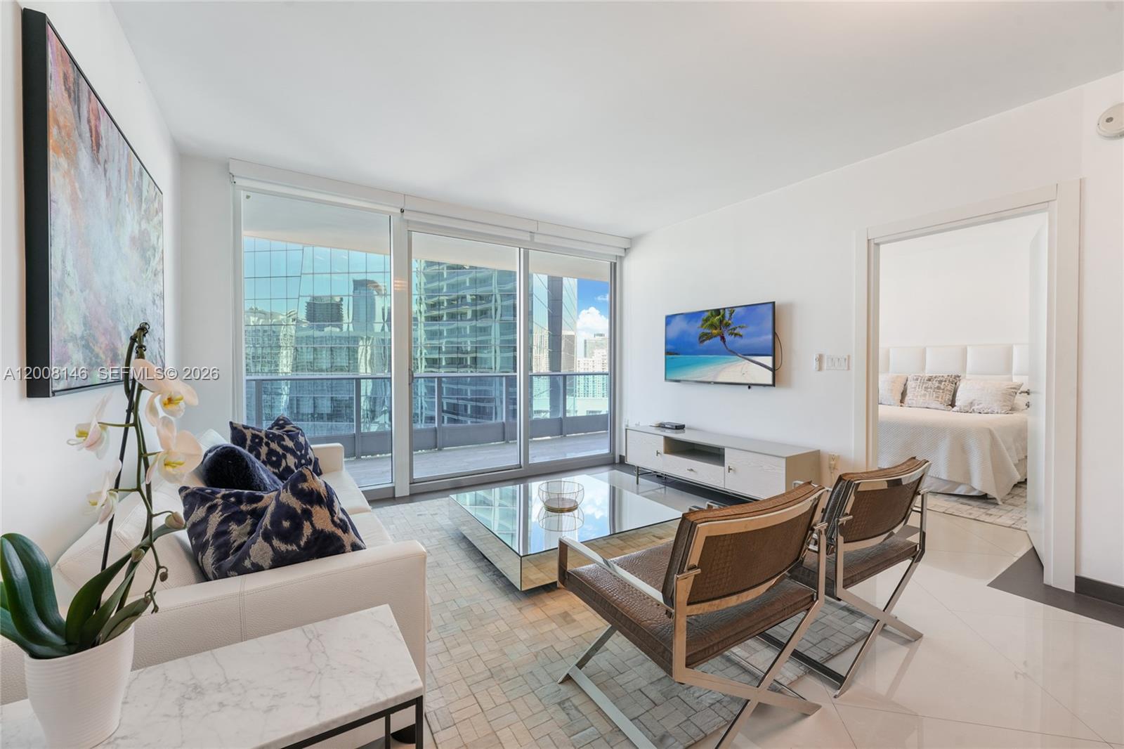 A modern living room features a white sofa, glass coffee table, and floor-to-ceiling windows — 200 Biscayne Boulevard Way # 3613, Miami FL 33131, MIAMI, FL