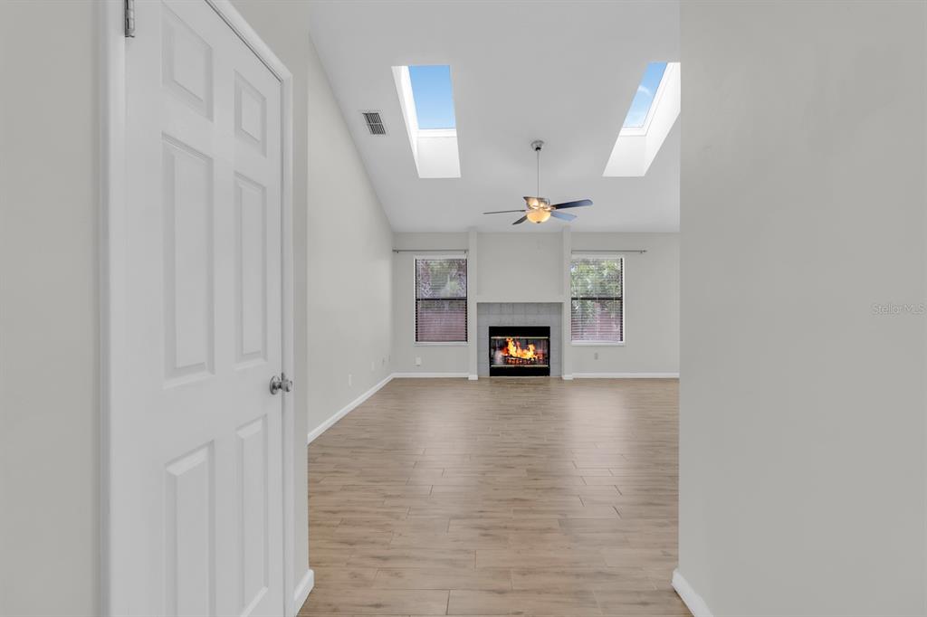 A living room with wood-look flooring, a fireplace, vaulted ceilings, and two skylights — 3152 S HORIZON PLACE, OVIEDO, FL
