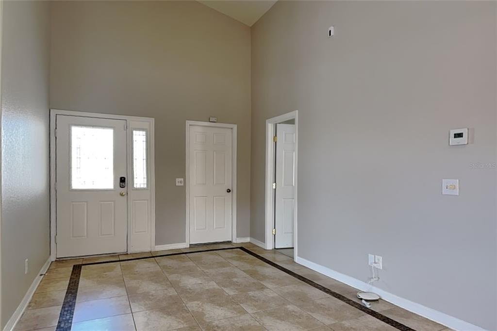 An entryway with vaulted ceilings, tiled floors, and three white doors — 229 LOOKOUT DRIVE, APOLLO BEACH, FL