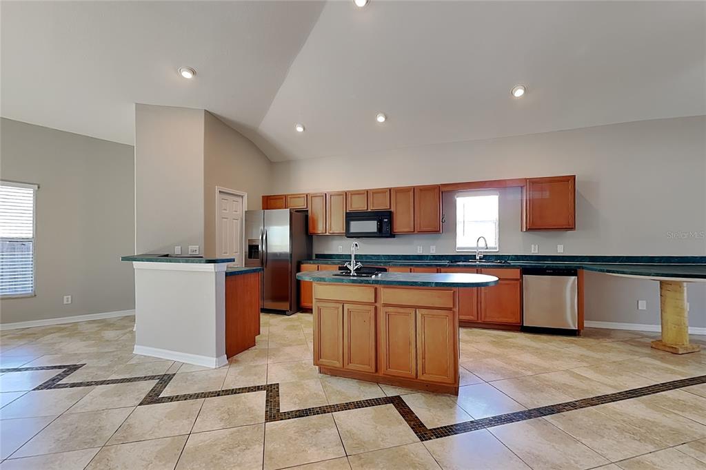 A kitchen features wood cabinets, green countertops, stainless steel appliances, and a tiled floor — 229 LOOKOUT DRIVE, APOLLO BEACH, FL