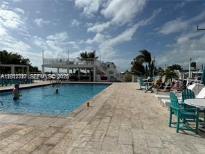 An outdoor swimming pool with a stone deck and lounge chairs under a blue sky — 325 Calusa St, Key Largo FL 33037, KEY LARGO, FL