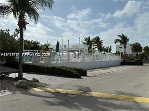 A fenced outdoor pool area with lounge chairs and palm trees under a blue sky — 325 Calusa St, Key Largo FL 33037, KEY LARGO, FL