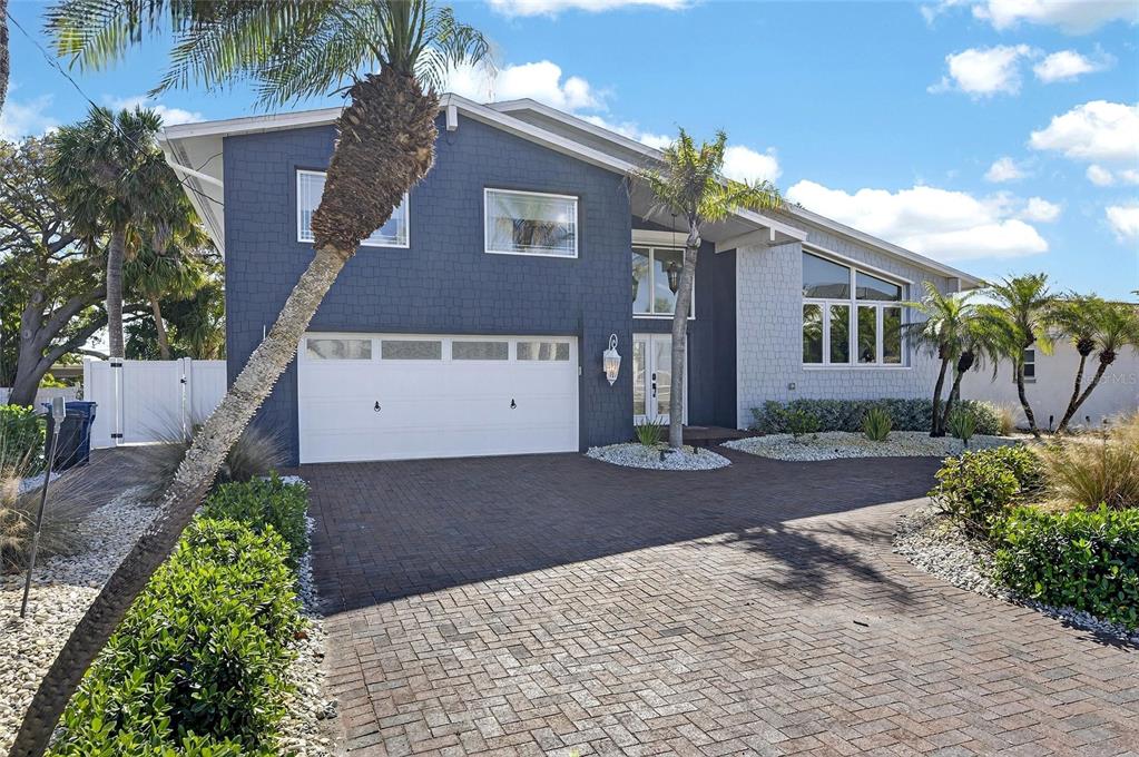 A two-story house with a blue textured facade, white garage door, and brick paver driveway — 931 GULF BOULEVARD, BELLEAIR BEACH, FL