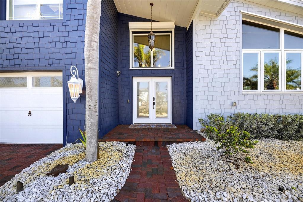 The exterior of a house features blue and white shingle siding, a brick walkway, and double doors — 931 GULF BOULEVARD, BELLEAIR BEACH, FL