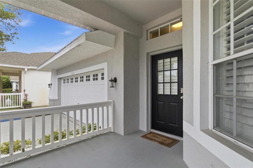 A covered front porch features a black door, white railing, and a garage entrance — 4613 CORSAGE DRIVE, LUTZ, FL