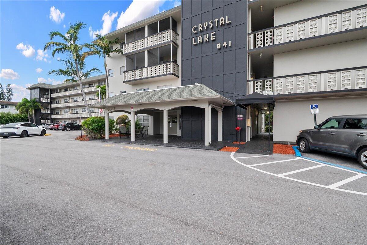 The exterior of a multi-story apartment building features a covered entrance and parking area — 941 Crystal Lake Drive # 402, Deerfield Beach FL 33064, DEERFIELD BEACH, FL