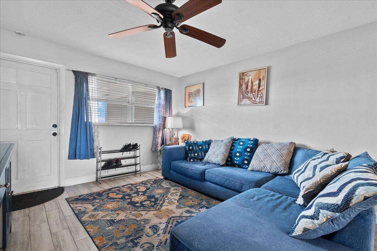 A living room features a blue sectional sofa, a patterned area rug, and a ceiling fan — 941 Crystal Lake Drive # 402, Deerfield Beach FL 33064, DEERFIELD BEACH, FL