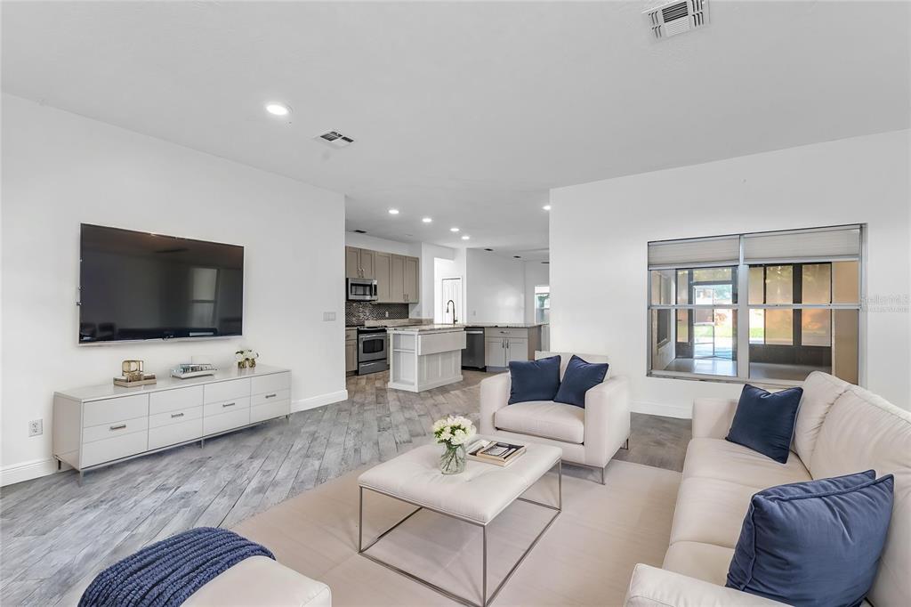 A living room with light wood-look tile flooring opens into a kitchen with white cabinets — 2031 WINTERMERE POINTE DRIVE, WINTER GARDEN, FL