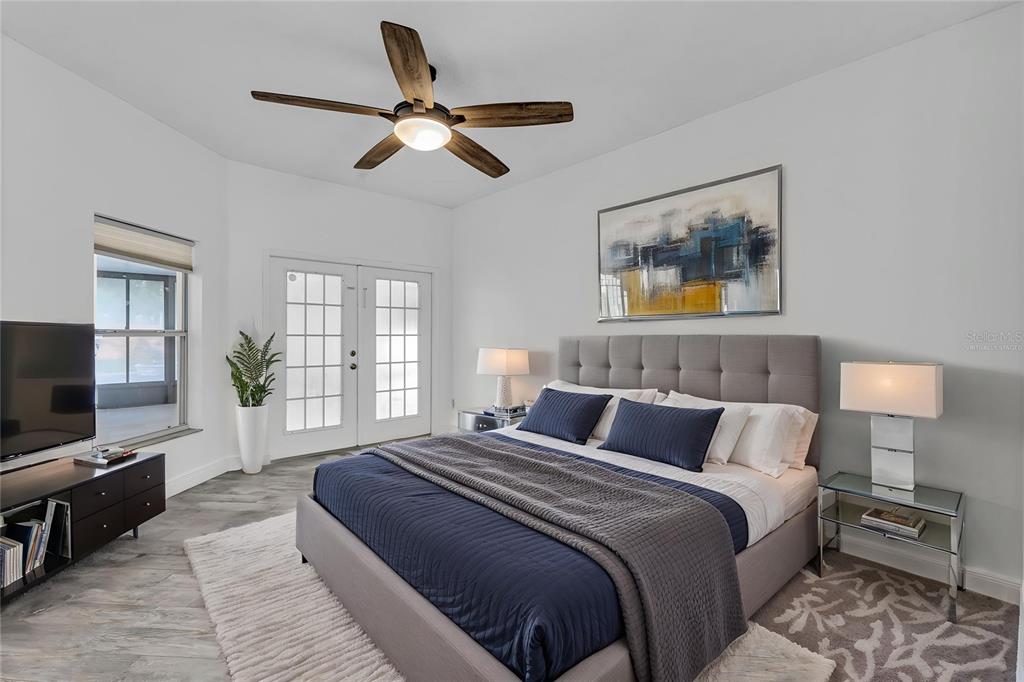 A bedroom features a gray upholstered bed, a ceiling fan, and French doors — 2031 WINTERMERE POINTE DRIVE, WINTER GARDEN, FL