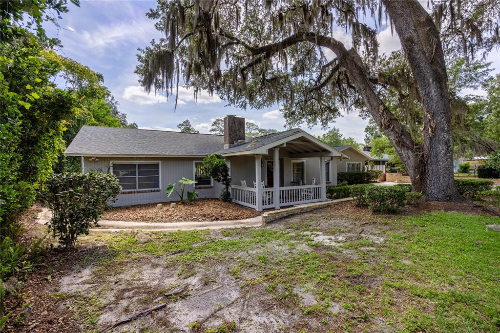 A single-story house with gray siding and a covered front porch sits under large trees — 3933 SE STATE ROAD 21, KEYSTONE HEIGHTS, FL