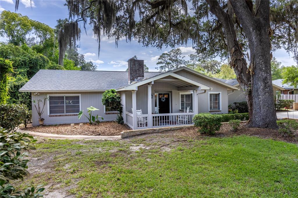 A single-story house with gray siding, a brick chimney, and a covered front porch — 3933 SE STATE ROAD 21, KEYSTONE HEIGHTS, FL