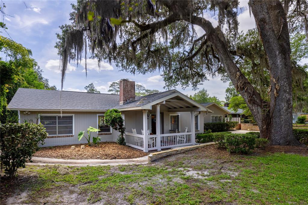 A single-story house with a covered porch, brick chimney, and large oak tree in front — 3933 SE STATE ROAD 21, KEYSTONE HEIGHTS, FL