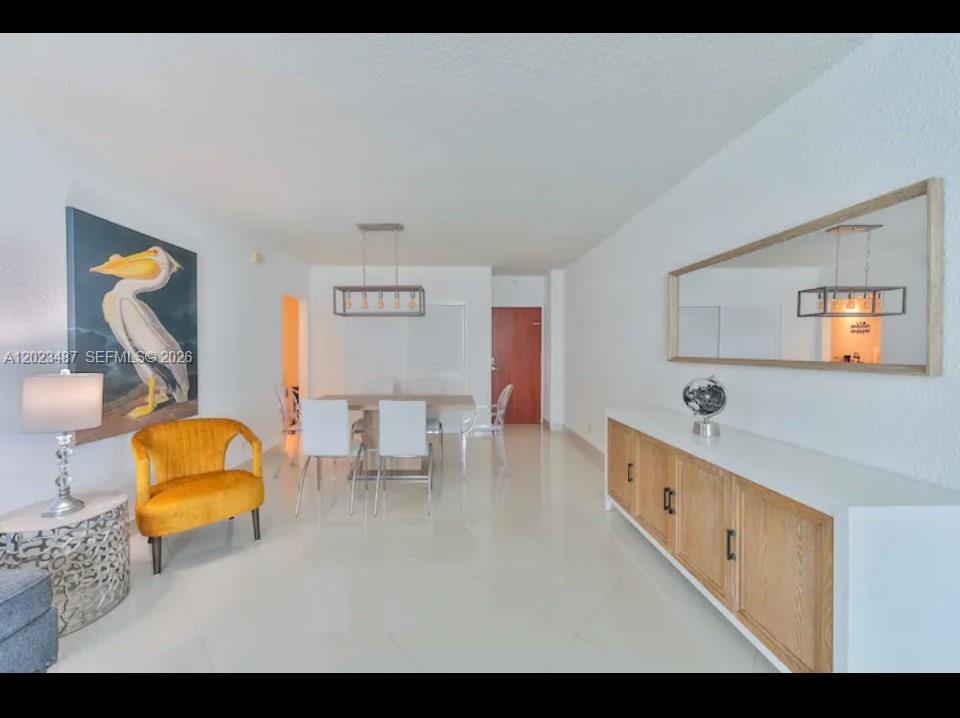 A dining area with a yellow chair, a wooden sideboard, and a large wall mirror — 4001 S Ocean Dr # 7L, Hollywood FL 33019, HOLLYWOOD, FL