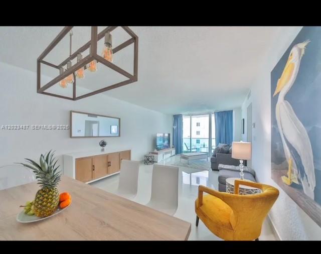 A bright, open-concept living and dining area features white tile floors, modern lighting, and coastal decor — 4001 S Ocean Dr # 7L, Hollywood FL 33019, HOLLYWOOD, FL