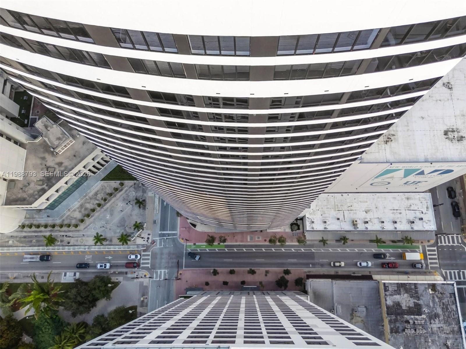 An aerial view shows a tall skyscraper overlooking a city street and surrounding buildings — 225 N Miami # 1705, Miami FL 33131, MIAMI, FL