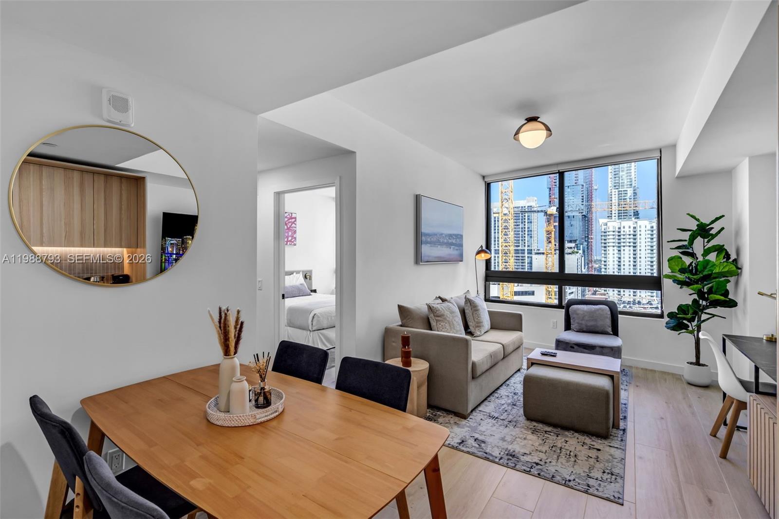 A modern apartment living and dining area features light wood floors and city skyline views — 225 N Miami # 1705, Miami FL 33131, MIAMI, FL