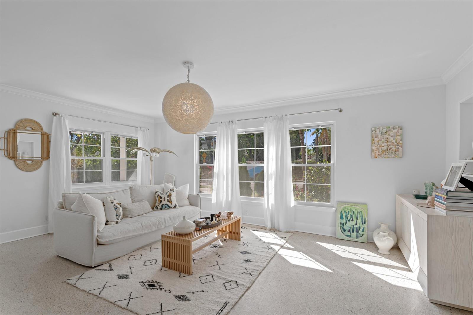 A bright living room features a white sofa, a slatted coffee table, and large windows — 143 Greymon Drive, West Palm Beach FL 33405, WEST PALM BEACH, FL