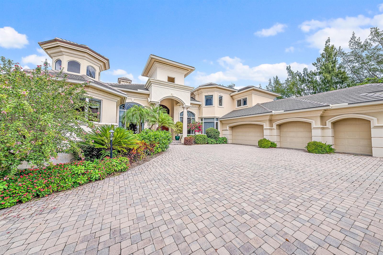 A large, multi-story beige house features a paved driveway and a three-car garage — 12049 SE Intracoastal Terrace, Jupiter FL 33469, JUPITER, FL