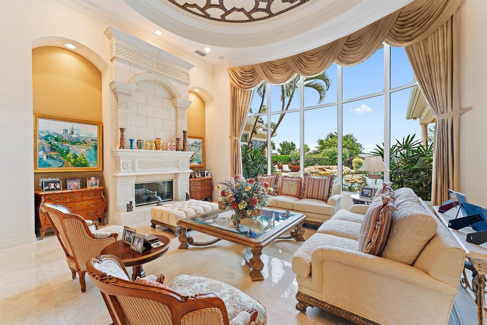 A formal living room features a stone fireplace, large windows, and elegant traditional furniture — 12049 SE Intracoastal Terrace, Jupiter FL 33469, JUPITER, FL