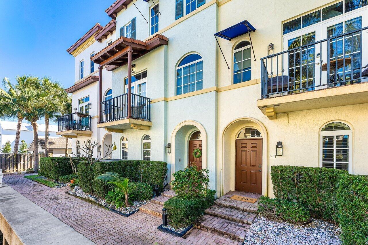 A multi-story townhouse exterior with balconies, arched doorways, and a brick walkway — 813 Estancia Way, Boynton Beach FL 33435, BOYNTON BEACH, FL