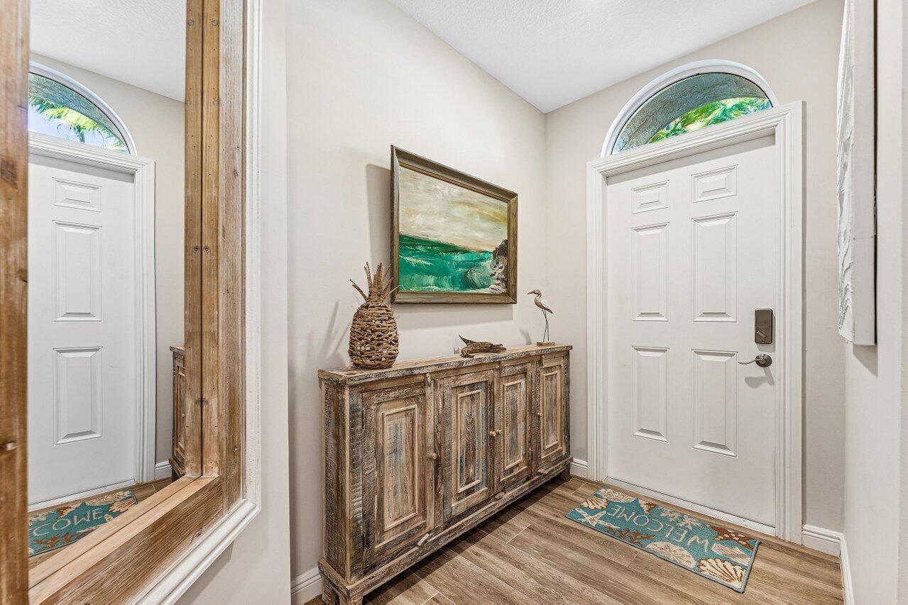 An entryway features a wooden console table, a coastal painting, and a white front door — 813 Estancia Way, Boynton Beach FL 33435, BOYNTON BEACH, FL