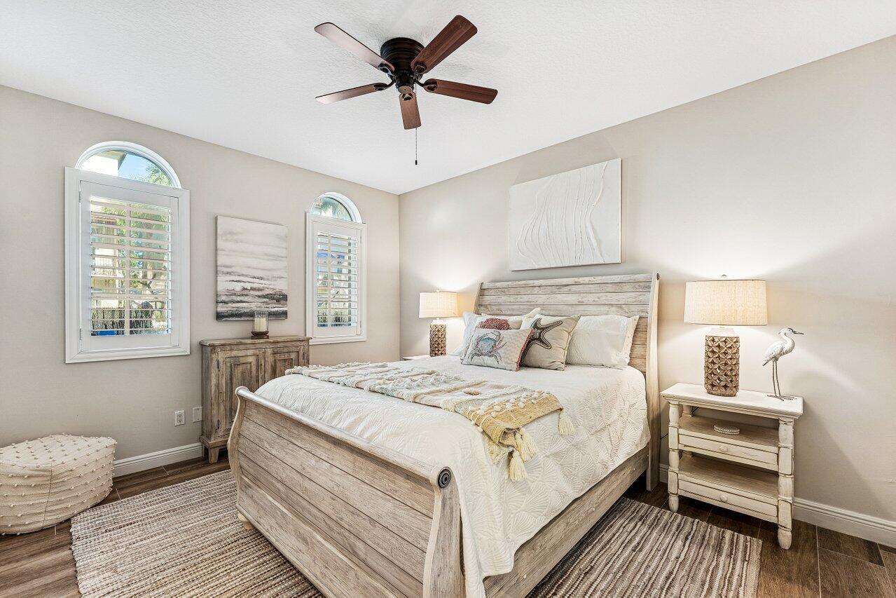A bedroom features a wooden bed, two nightstands, a ceiling fan, and arched windows — 813 Estancia Way, Boynton Beach FL 33435, BOYNTON BEACH, FL