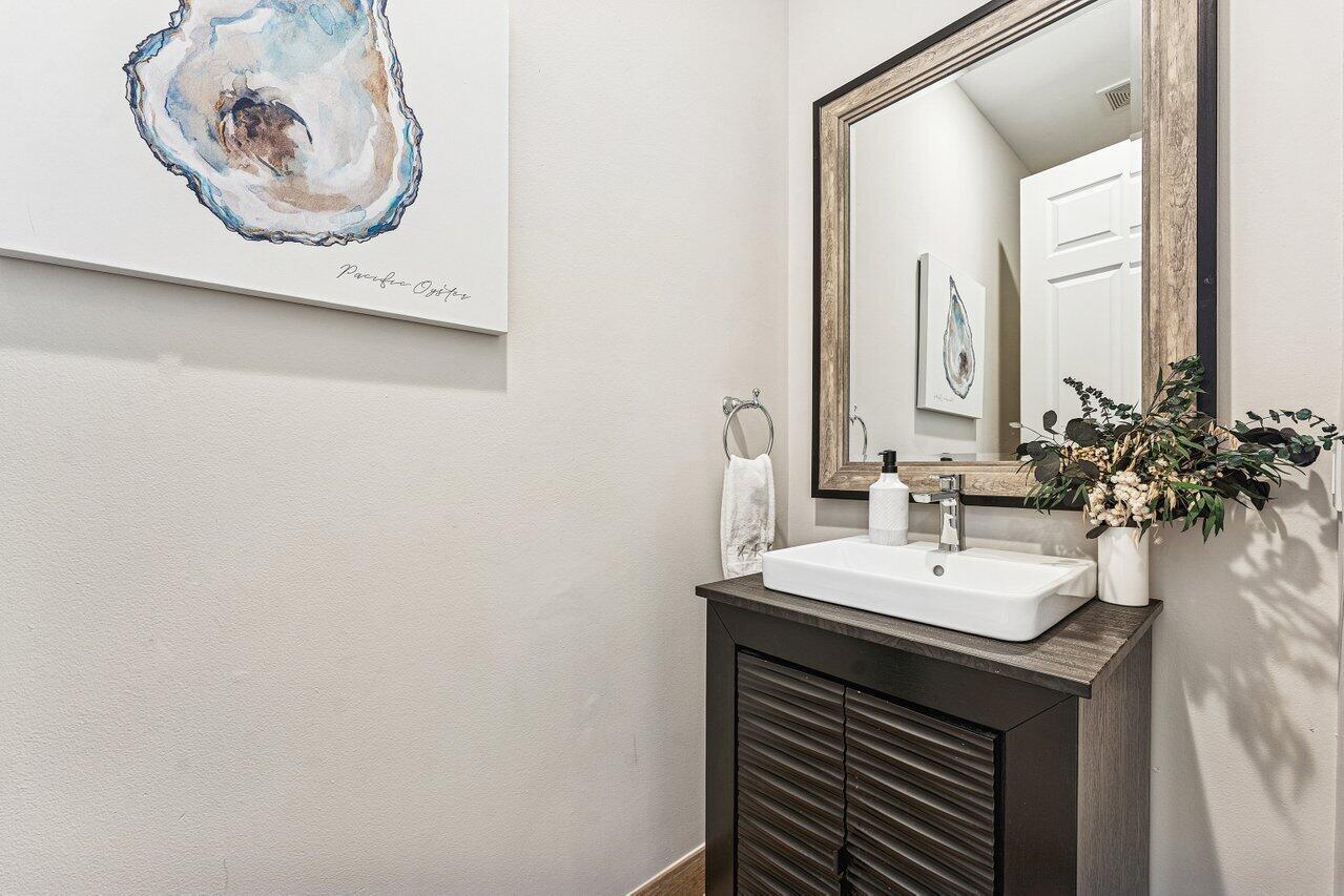 A powder room features a dark wood vanity, a vessel sink, and an oyster print — 813 Estancia Way, Boynton Beach FL 33435, BOYNTON BEACH, FL
