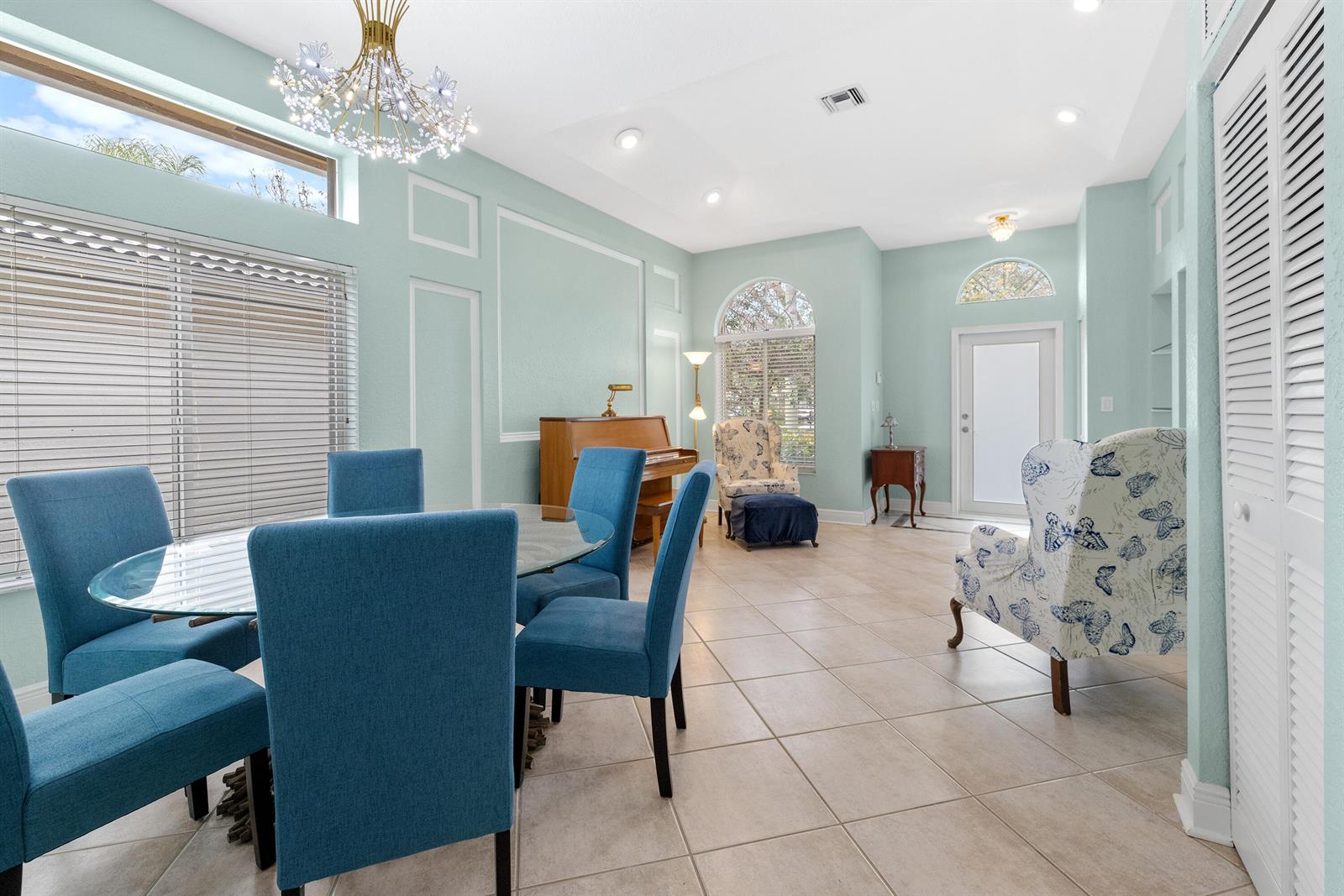 A dining room with blue chairs, a glass table, a piano, and light green walls — 6513 Sandpiper Drive, Coconut Creek FL 33073, COCONUT CREEK, FL