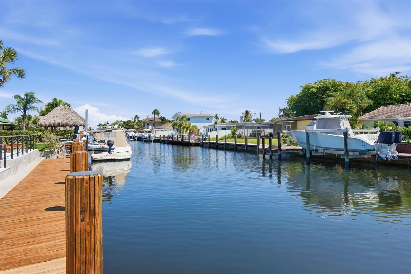 A wooden dock extends along a canal lined with houses and several docked boats — 2280 SE 10th Court, Pompano Beach FL 33062, POMPANO BEACH, FL