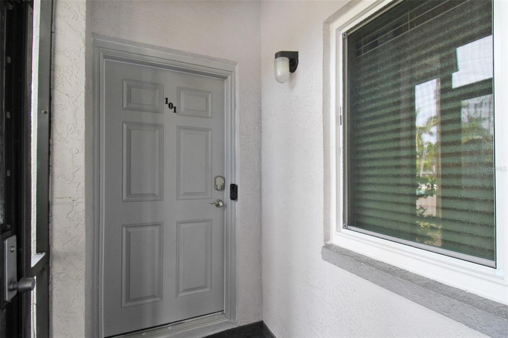 A grey front door with the number 101 sits beside a window on a porch — 2124 N TAMIAMI TRAIL UNIT 101, SARASOTA, FL