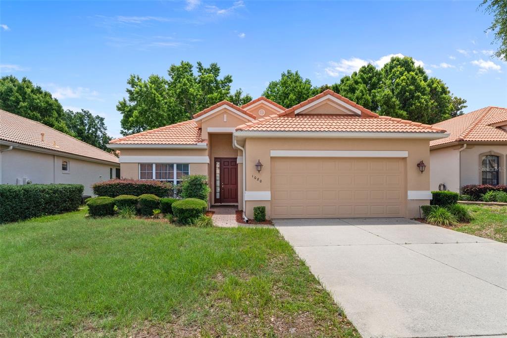 A single-story house with a tan stucco exterior, tile roof, and a two-car garage — 1080 W SKYVIEW CROSSING DRIVE, HERNANDO, FL