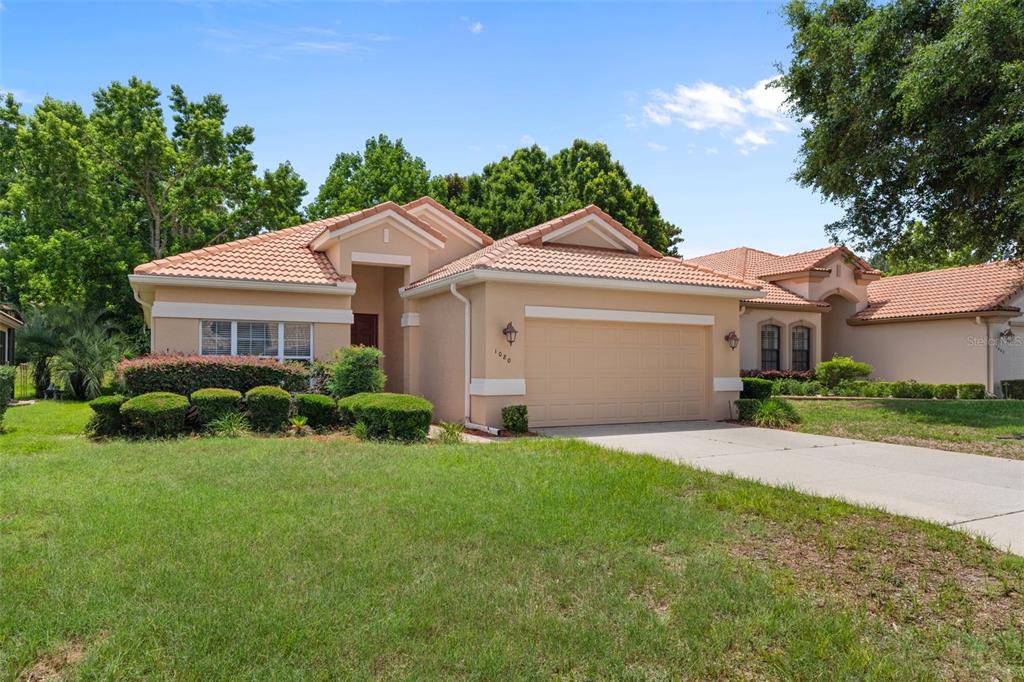 A single-story house with a tan stucco exterior, a tile roof, and a two-car garage — 1080 W SKYVIEW CROSSING DRIVE, HERNANDO, FL