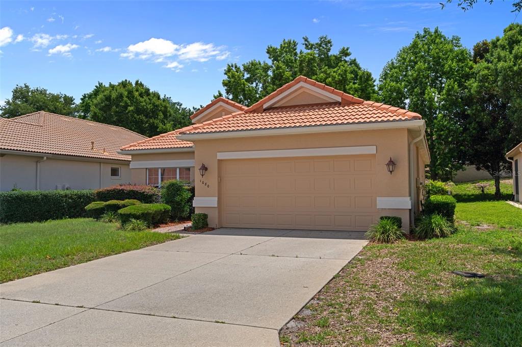 A single-story house with a tan stucco exterior, a tiled roof, and a two-car garage — 1080 W SKYVIEW CROSSING DRIVE, HERNANDO, FL