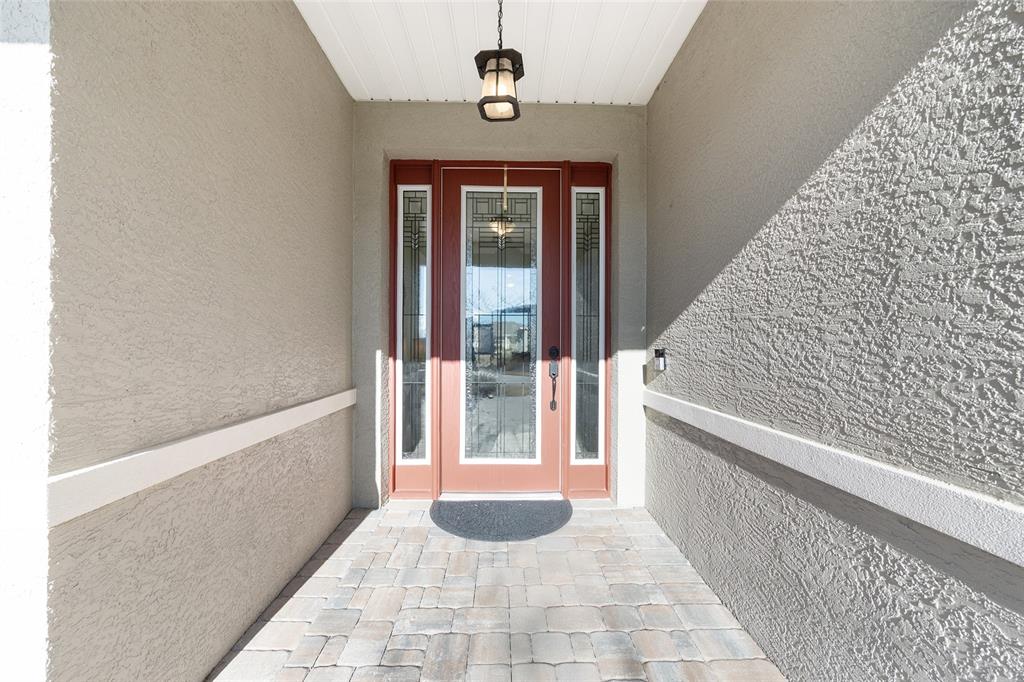 A front entryway features a red door with glass panels, a paver floor, and stucco walls — 8111 SW 95TH COURT, OCALA, FL