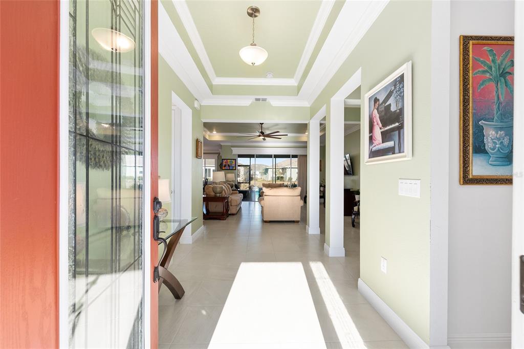 A view from a front doorway into a bright foyer with tray ceilings and tile floors — 8111 SW 95TH COURT, OCALA, FL