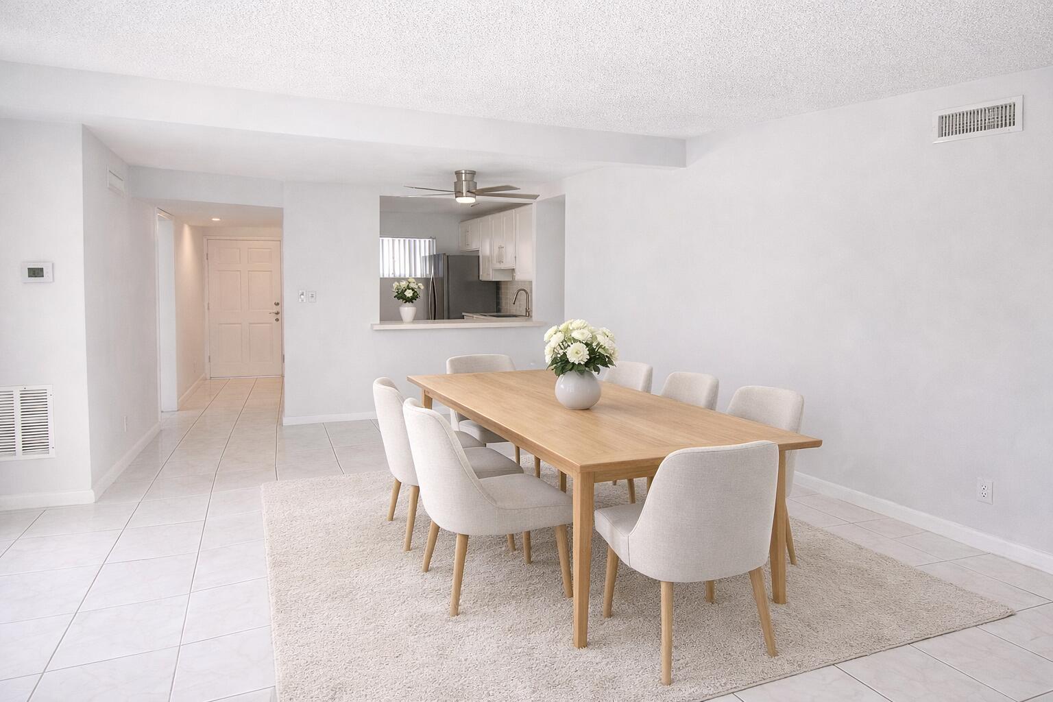 A dining room features a wooden table with eight chairs on a light-colored area rug — 2687 Garden Drive N # 212, FL 33461, FL