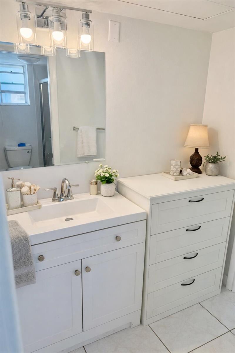 A white bathroom vanity with a sink sits next to a matching four-drawer dresser — 2687 Garden Drive N # 212, FL 33461, FL