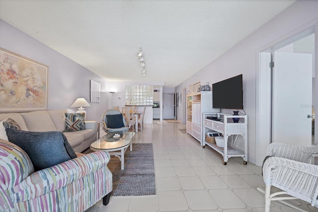 A living room with light tile floors, a sofa, a television, and a dining area — 500 S WASHINGTON DRIVE UNIT 5B, SARASOTA, FL