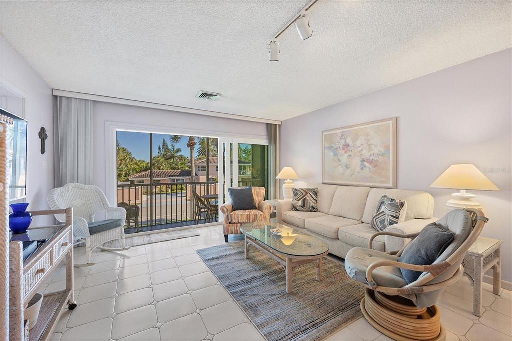 A living room features tile flooring, a beige sofa, wicker chairs, and a sliding glass door — 500 S WASHINGTON DRIVE UNIT 5B, SARASOTA, FL